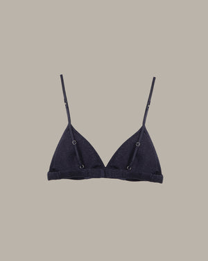 Black bralette with thin straps on a beige background