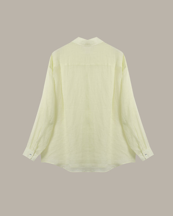 A pale yellow-green long-sleeve blouse shown from the back, featuring a high collar and buttoned cuffs, set against a solid taupe background.