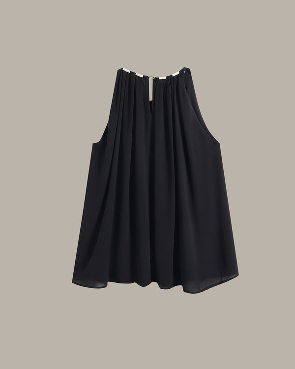 A sleeveless black pleated top with a split neckline and a small silver metal accent at the center, displayed against a solid taupe background.