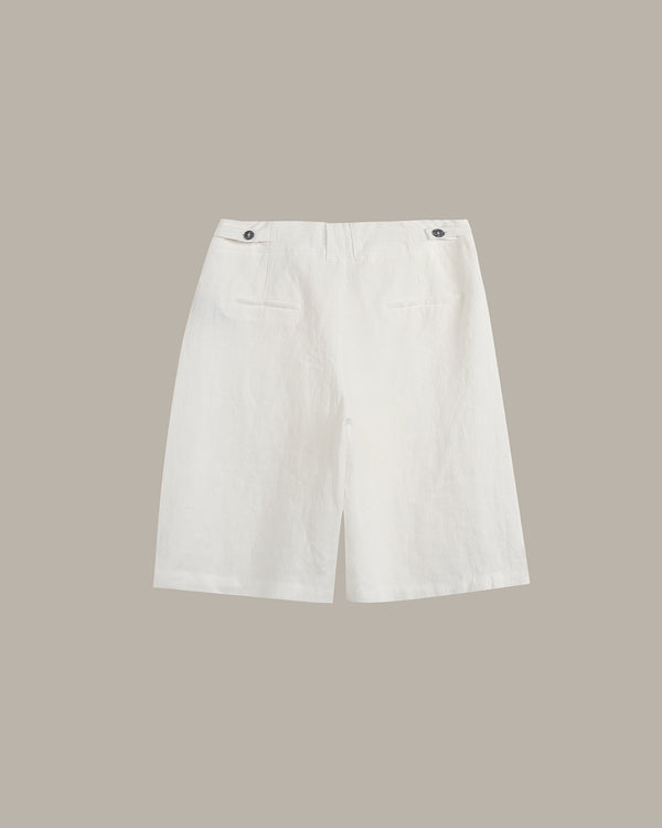 White linen shorts with a relaxed fit, featuring two buttoned flap pockets on the back, displayed against a solid taupe background.