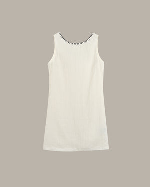White sleeveless dress with black trim on a beige background