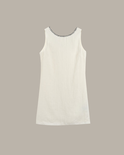White sleeveless dress with black trim on a beige background