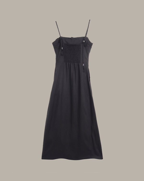 Black dress with thin straps on a beige background
