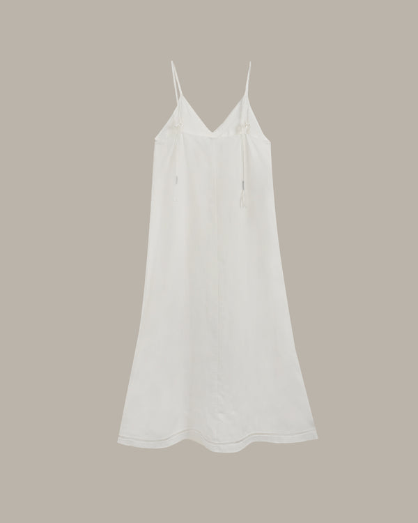 A white spaghetti-strap slip dress with a V-neckline, shown against a solid taupe background.
