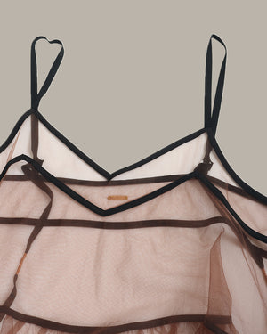 Sheer top with black straps on a neutral background