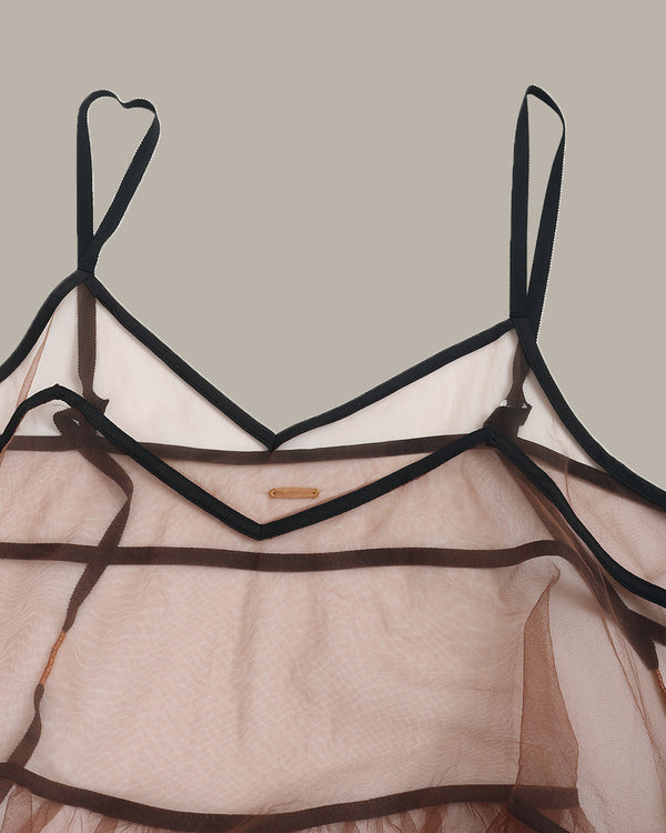 Sheer top with black straps on a neutral background