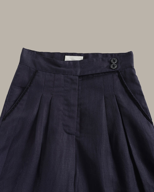 Navy blue pleated skirt with a button detail on a neutral background
