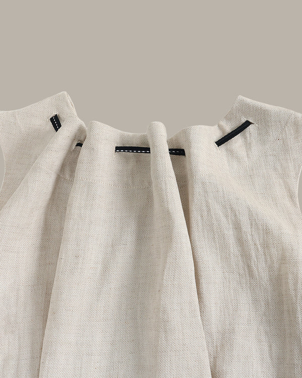Two beige linen shirts hanging on a rack against a neutral background