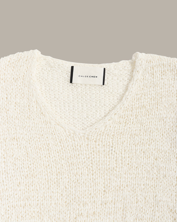 Close-up of a textured cream knit sweater with a V-neck collar, featuring a white neck label with black text that reads 'CHLOE CHEN'.