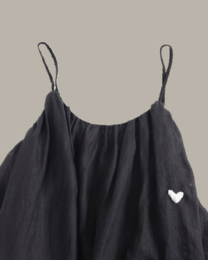 Black dress with thin straps on a beige background