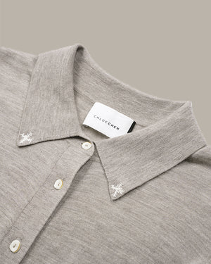 Close-up of a light gray knit polo shirt collar with white buttons and embroidered floral details on the points, featuring a visible CHLOE CHEN neck label.
