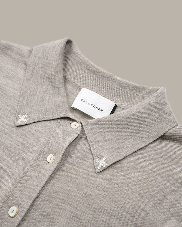 Close-up of a light gray knit polo shirt collar with white buttons and embroidered floral details on the points, featuring a visible CHLOE CHEN neck label.