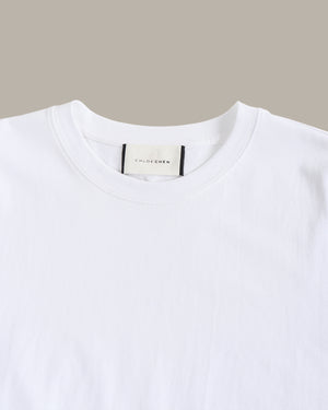 White t-shirt with a visible brand label on a beige background
