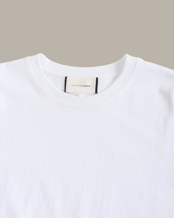 White t-shirt with a visible brand label on a beige background