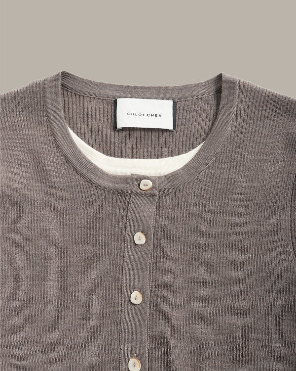 Close-up of a ribbed knit Henley shirt by Chloé Ché, in a taupe-brown color, featuring a white inner collar and light-colored buttons.