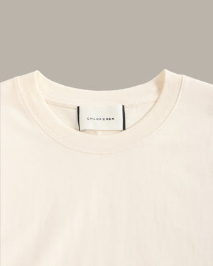 Close-up of a beige sweater with a brand label on a gray background