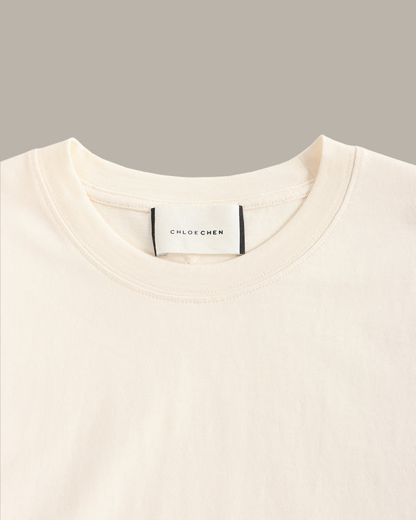 Close-up of a beige sweater with a brand label on a gray background