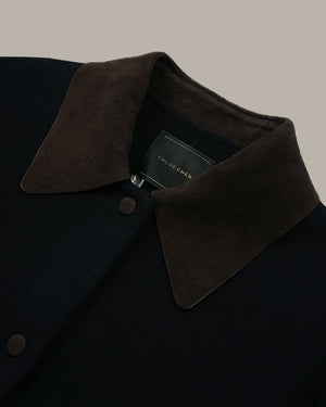 Close-up of a dark navy wool coat with a contrasting dark brown suede collar, featuring a button closure and a visible CLOCHESNE label.