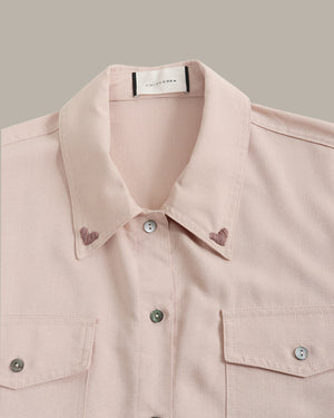 Close-up of a light pink shirt with collar and buttons on a neutral background
