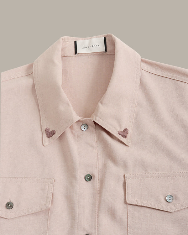 Close-up of a light pink shirt with collar and buttons on a neutral background