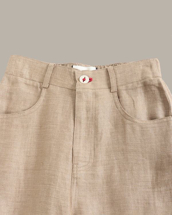 Close-up of beige pants with a button and zipper on a neutral background