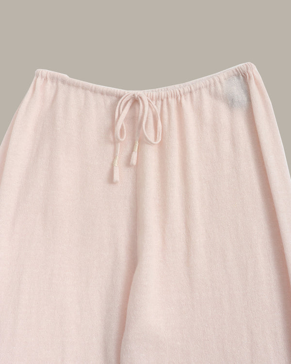 Close-up of a light blush pink drawstring lounge pant leg, showing the soft textured fabric and elastic waistband against a solid neutral background.
