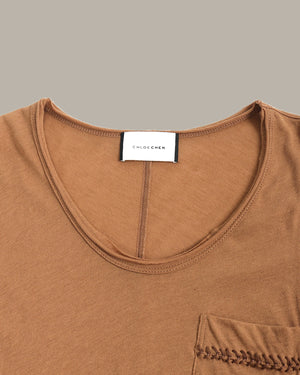 Close-up of a brown garment with a visible brand label on a gray background