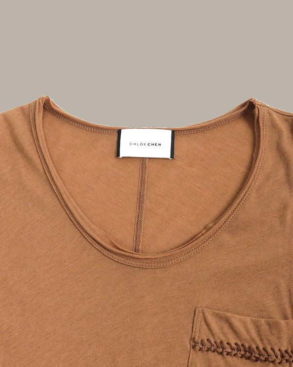 Close-up of a brown garment with a visible brand label on a gray background
