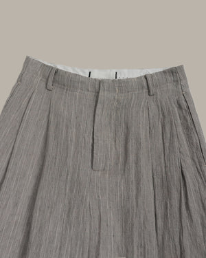 Close-up of gray pleated pants on a beige background