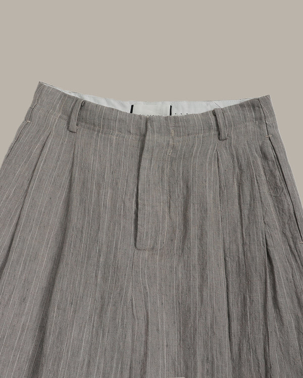 Close-up of gray pleated pants on a beige background