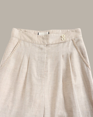 Beige pants with a button detail on a gray background