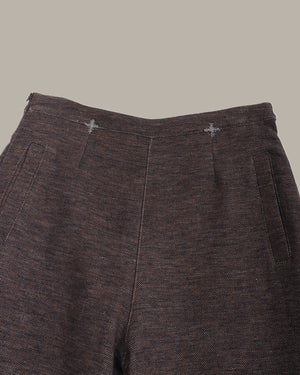 Close-up of dark brown textured pants on a gray background
