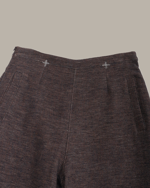 Close-up of dark brown textured pants on a gray background