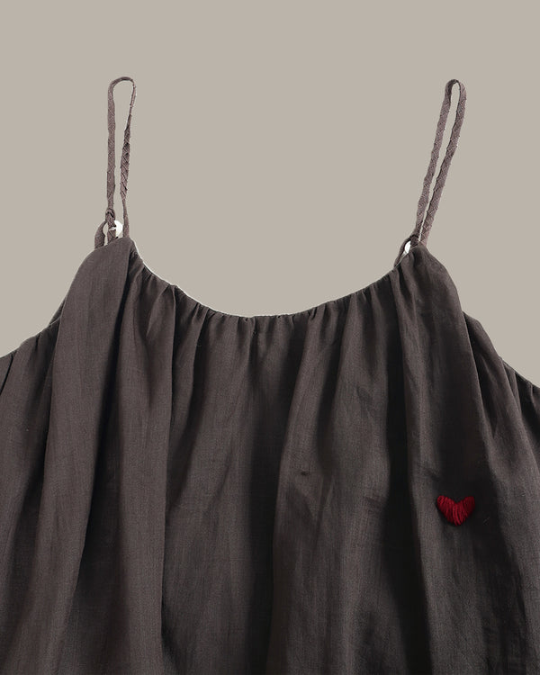 Dark gray dress with thin straps and a red heart detail on a beige background