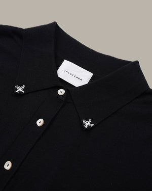 Close-up of a black knit polo shirt collar with silver-toned decorative studs and a white neck label reading CHLOE CHEN.