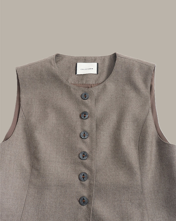 A sleeveless taupe-gray linen vest with a button-down front and a white neck label reading 'CROCHET CLOTHING', shown against a solid taupe background.