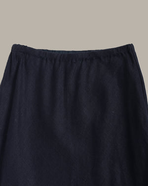 Close-up of a dark navy blue skirt fabric with an elastic waistband, shown against a solid light gray background.