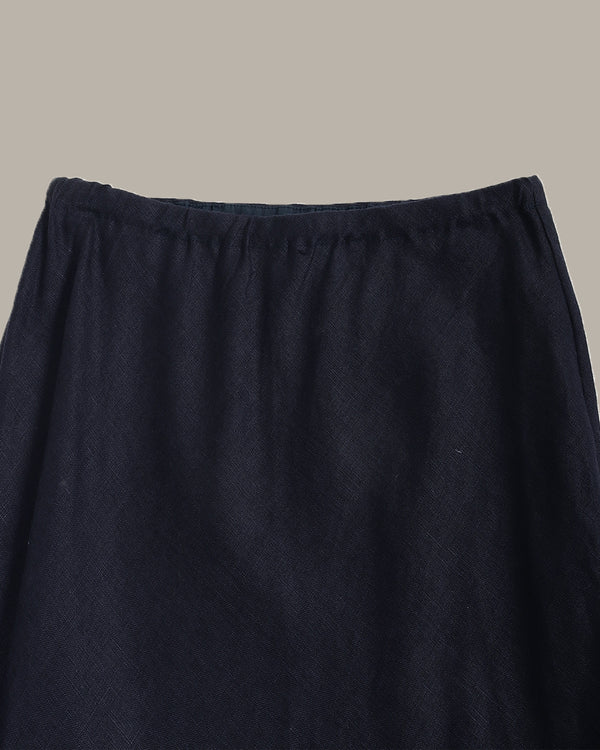 Close-up of a dark navy blue skirt fabric with an elastic waistband, shown against a solid light gray background.