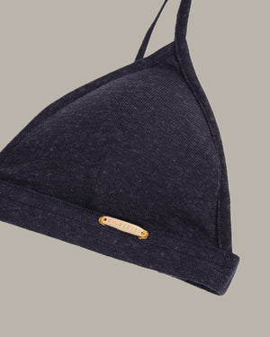 Navy blue bikini top with a brand label on a beige background