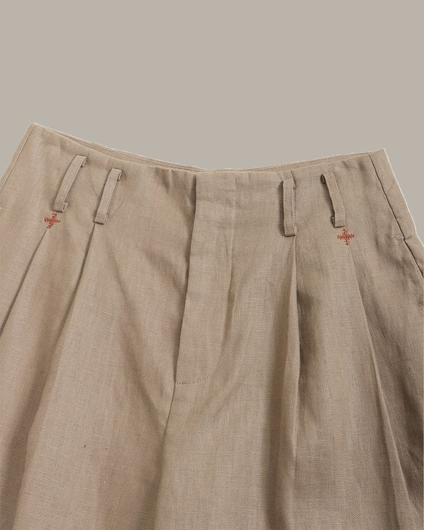 Beige pants with small red logos on a neutral background