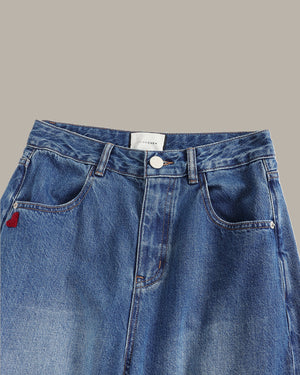 Blue denim jeans with a brand label on a gray background