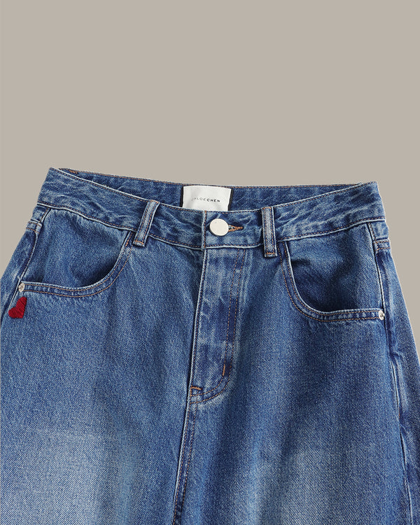 Blue denim jeans with a brand label on a gray background