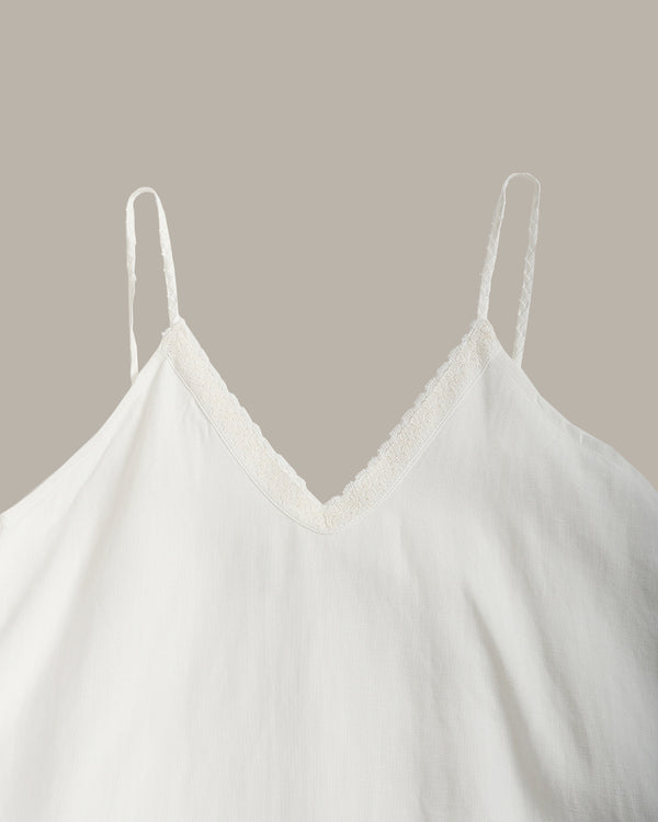 White camisole top with thin spaghetti straps and a delicate lace V-neckline, shown against a solid taupe background.