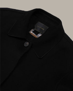 Close-up of a black wool-blend coat collar with a single button and a visible black brand label reading Dries Van Noten.