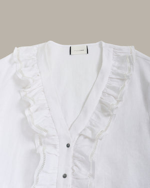 White blouse with ruffled details on a light gray background