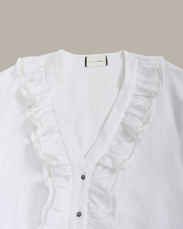White blouse with ruffled details on a light gray background