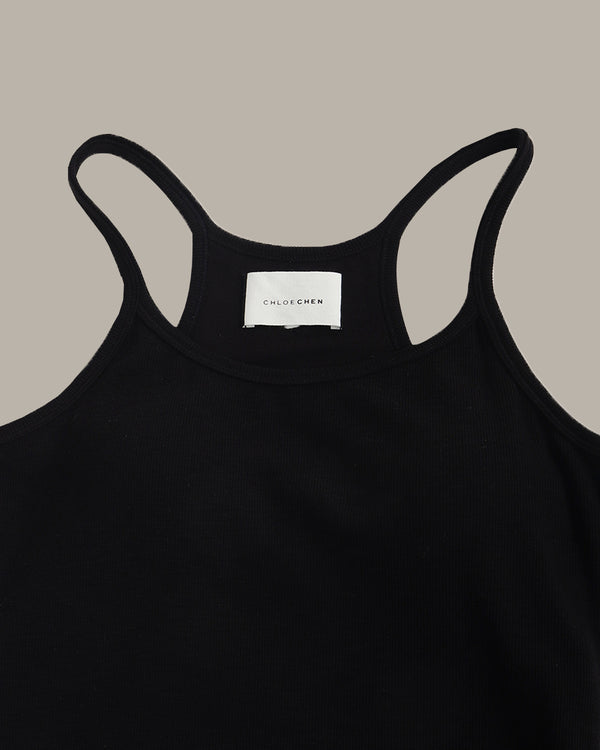 Black tank top with a visible brand label on a beige background