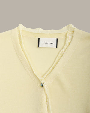 Light yellow cardigan with a brand label on a gray background