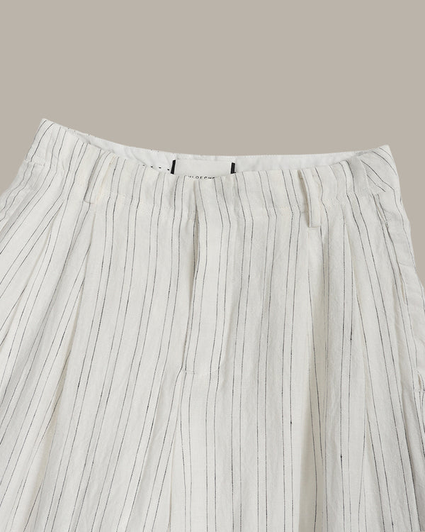 Close-up of pleated white pants with thin black stripes on a beige background