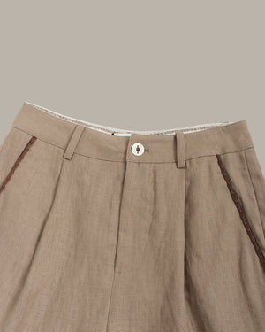 Close-up of brown pants with a button on a beige background